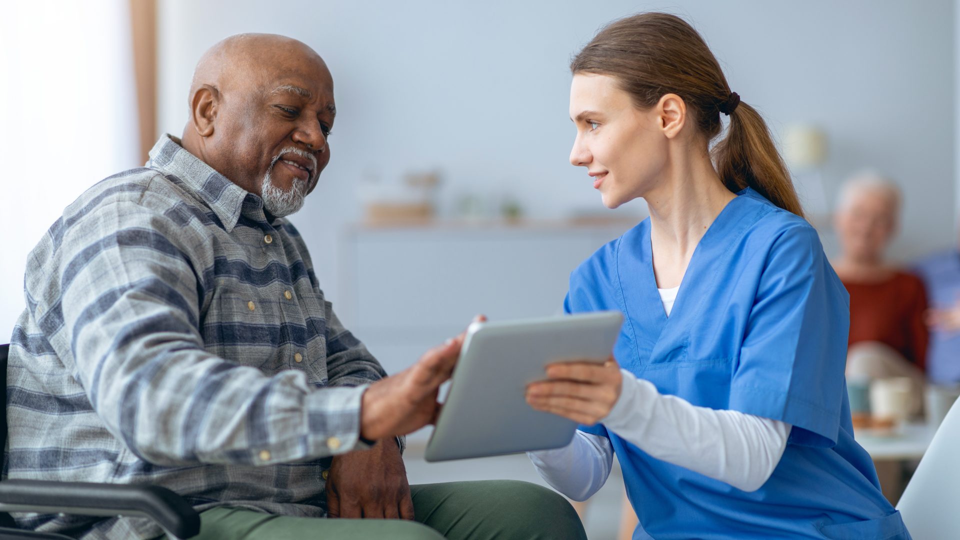 female doctor looking at an ipad with an older male patient